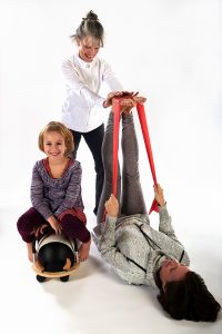 A girl with two women using physical therapy equipment