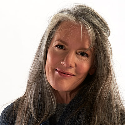 Headshot of a woman with gray hairs and bangs